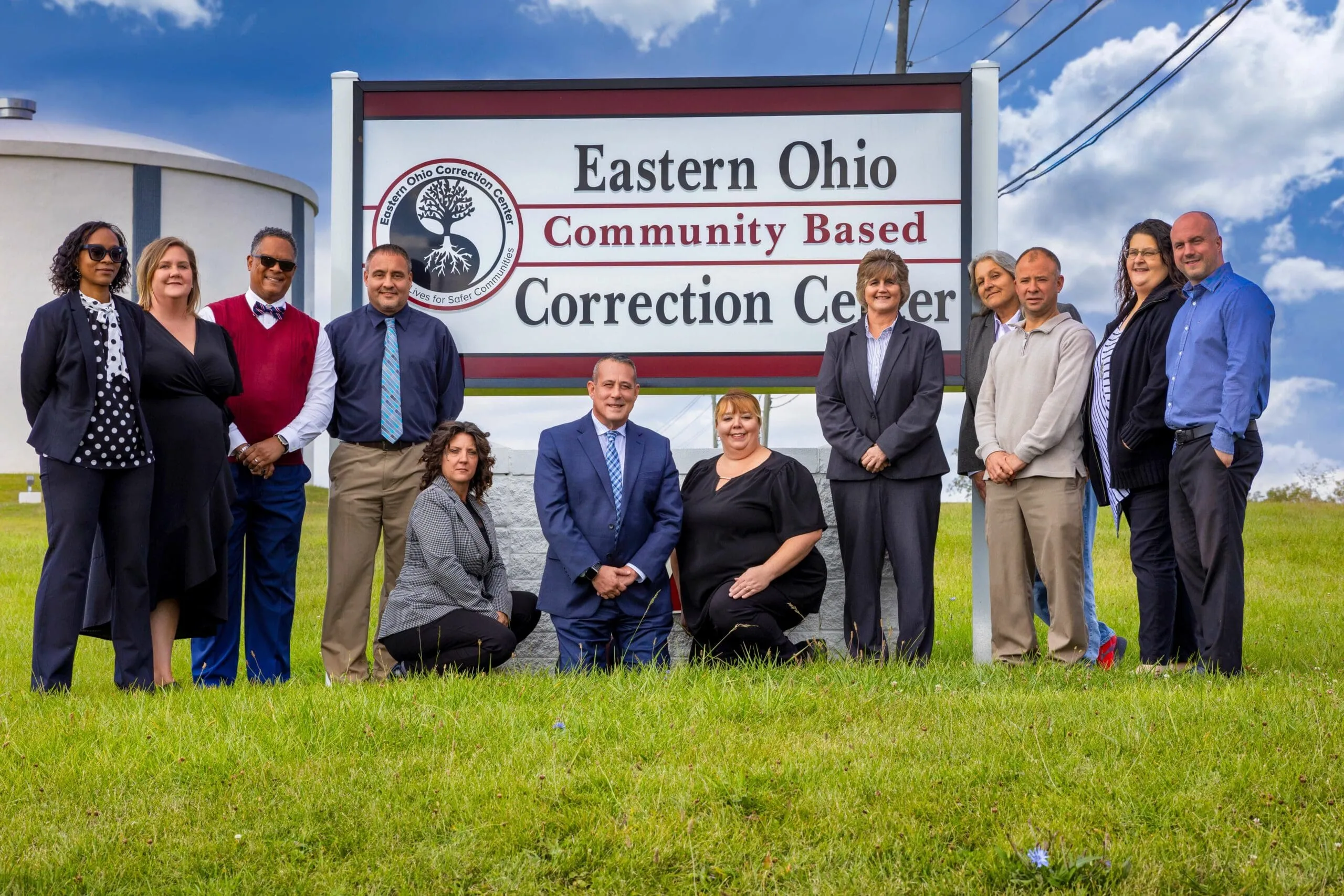The EOCC leadership and staff standing together in front of the Eastern Ohio Community Based Correction Center sign